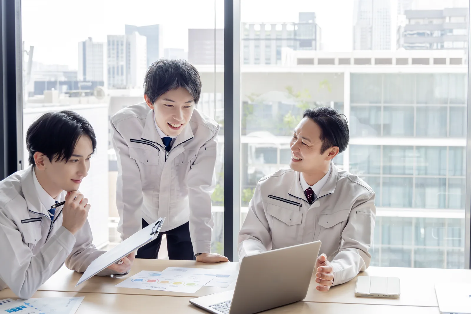 建設会社の担当者が見積書や工程資料を確認しながら打ち合わせるイメージ